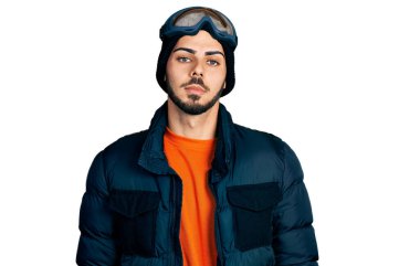 Kar giysileri ve gökyüzü gözlüğü takan sakallı İspanyol genç adam yüzünde ciddi bir ifadeyle rahatladı. Basit ve doğal bir şekilde kameraya bakıyorsun.. 
