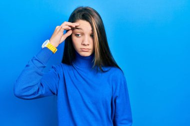 Young brunette girl wearing turtleneck sweater worried and stressed about a problem with hand on forehead, nervous and anxious for crisis 