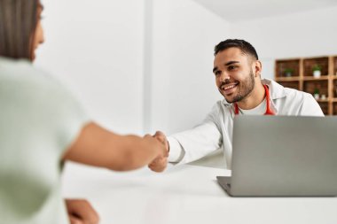 Klinikteki Latin kadın hastayla el sıkışan doktor..