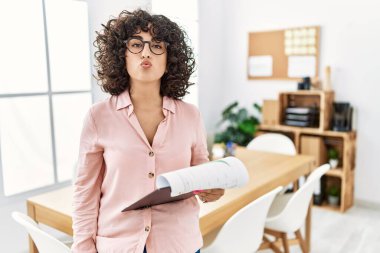 Young middle eastern woman wearing business style at office looking at the camera blowing a kiss on air being lovely and sexy. love expression. 