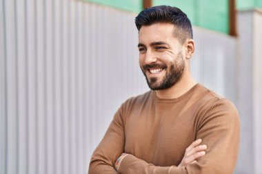 Genç İspanyol adam gülümsüyor. Kendine güveni tam. Sokakta çapraz hareketlerle duruyor.