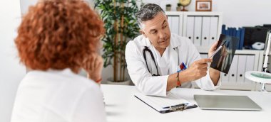 Doktor üniforması giyen orta yaşlı bir adam ve kadın klinikte tıbbi danışmanlık yapıyorlar.