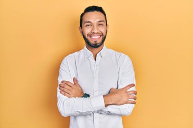 Hispanic man with beard wearing business shirt happy face smiling with crossed arms looking at the camera. positive person. 