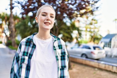 Modern beyaz saç stili ile genç ve güzel bir kadın dışarıda mutlu bir şekilde gülümsüyor.