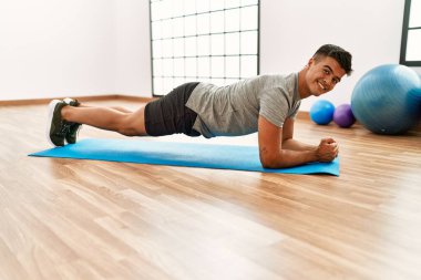 Genç İspanyol adam gülümsüyor spor merkezinde kendine güvenen karın kasları egzersizi yapıyor.