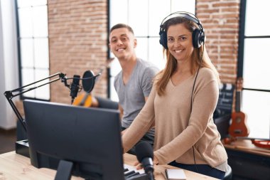 Erkek ve kadın müzisyenler müzik stüdyosunda piyano çalıyor.