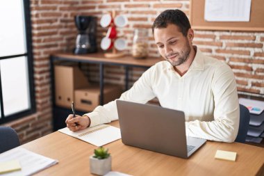 Young man business worker using laptop writing on notebook at office