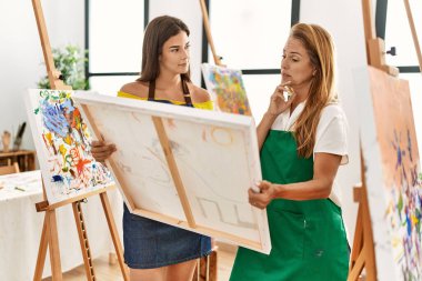 Mother and daughter looking draw canvas at art studio