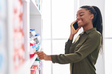 Afrika kökenli Amerikalı kadın müşteriler akıllı telefonlarıyla eczanede konuşuyorlar.