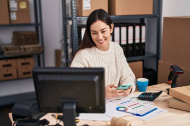 Ofiste akıllı telefon kullanan genç bir iş kadını.