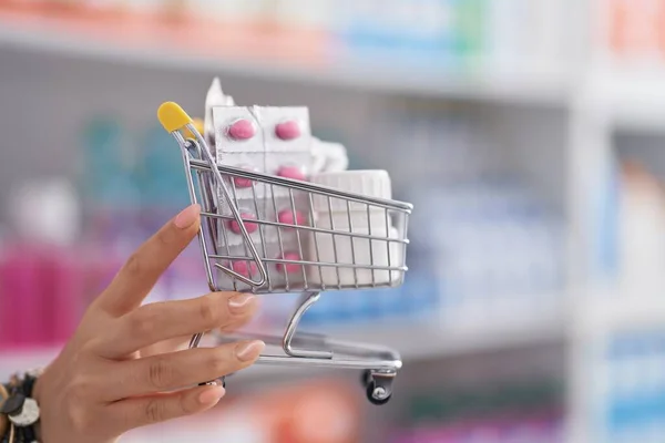 Chinese woman pharmacist holding shopping cart with pills at pharmacy