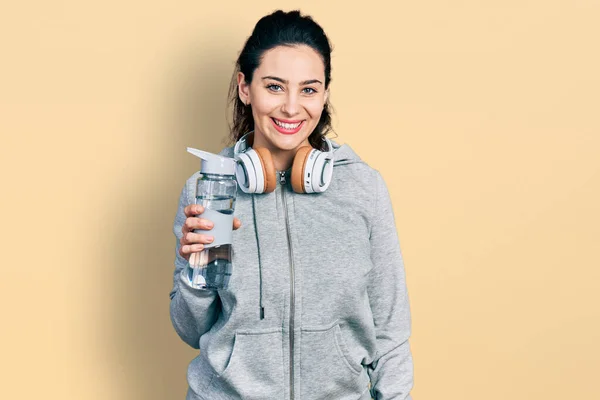 Young Hispanic Woman Wearing Sportswear Holding Water Bottle Using Headphones — Zdjęcie stockowe