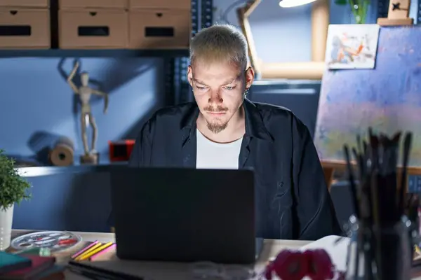 Young Caucasian Man Using Laptop Night Art Studio Skeptic Nervous — Stok fotoğraf