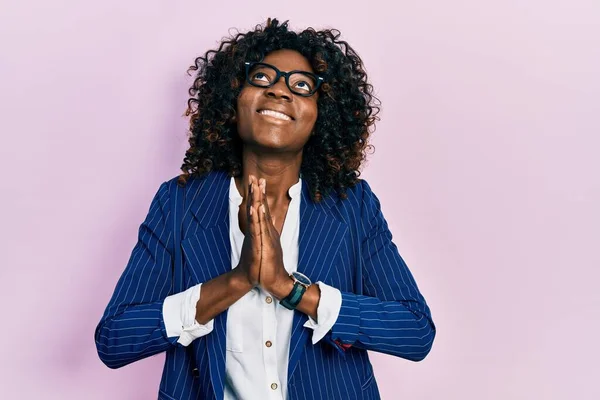 Young african american woman wearing business clothes and glasses begging and praying with hands together with hope expression on face very emotional and worried. begging.