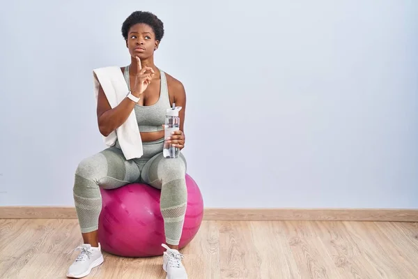 African American Woman Wearing Sportswear Sitting Pilates Ball Thinking Concentrated — Stockfoto