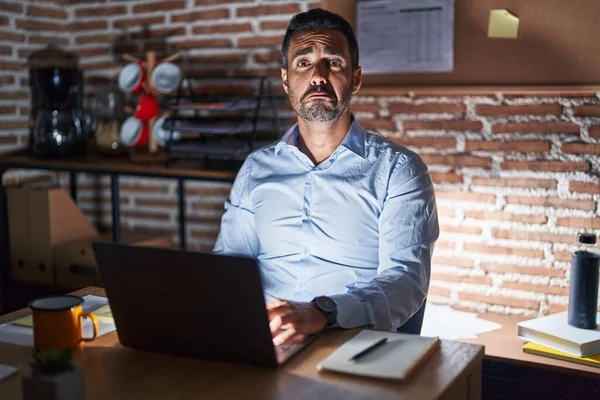 Hispanic man with beard working at the office at night depressed and worry for distress, crying angry and afraid. sad expression.