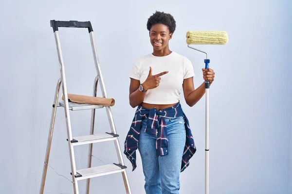 African American Woman Holding Roller Painter Cheerful Smile Face Pointing — Foto Stock
