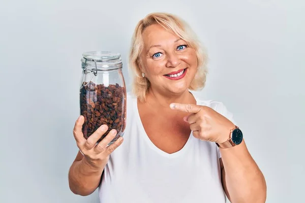 Middle Age Blonde Woman Holding Raisins Bowl Smiling Happy Pointing — Fotografia de Stock