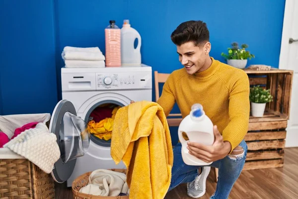 年轻人在洗衣店洗衣服 手里拿着洗涤剂瓶子 — 图库照片