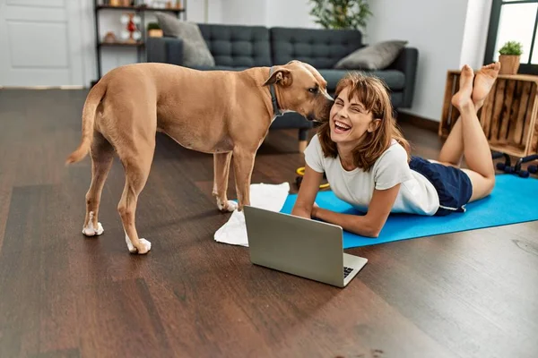 年轻的高加索女运动员微笑着 自信地用笔记本电脑和狗一起呆在家里 — 图库照片