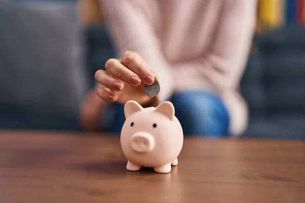 Young Woman Inserting Coin Piggy Bank Home — 스톡 사진
