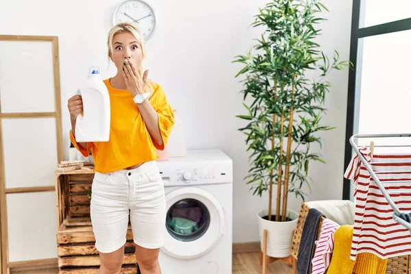 Young Caucasian Woman Doing Laundry Holding Detergent Bottle Covering Mouth — ストック写真
