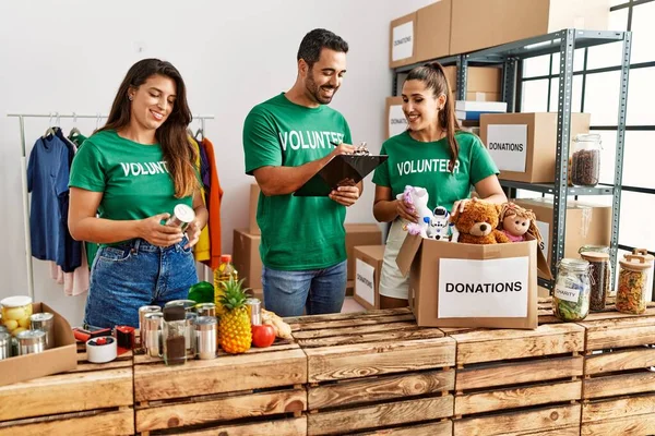 Group of hispanic volunteers smiling happy working at charity center.