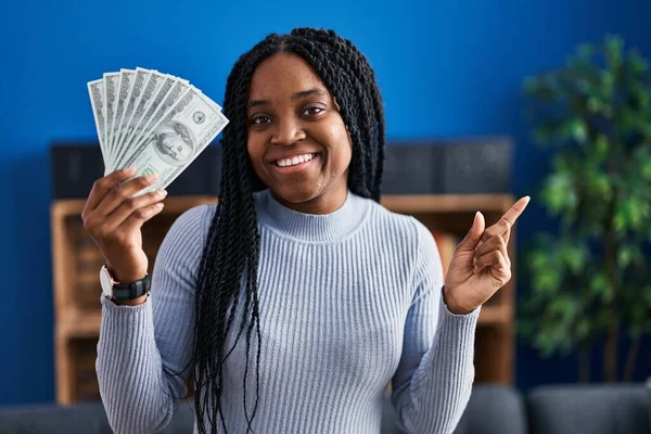African American Woman Holding Dollars Banknotes Smiling Happy Pointing Hand — Stock fotografie