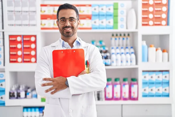 Jovem Hispânico Homem Farmacêutico Sorrindo Confiante Segurando Prancheta Farmácia — Fotografia de Stock