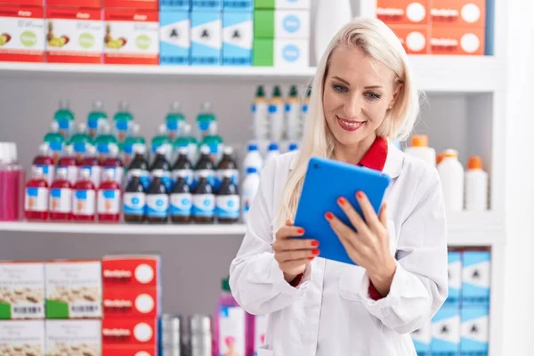 Young Blonde Woman Pharmacist Using Touchpad Working Pharmacy —  Fotos de Stock