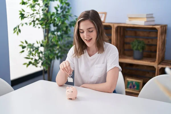 Young Woman Inserting House Key Piggy Bank Home — ストック写真