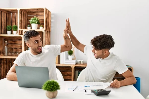 Два Латиноамериканца Подняли Руки Используя Ноутбук Работающий Дома — стоковое фото