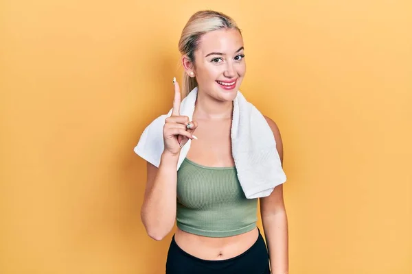 Ung Blond Flicka Bär Sportkläder Och Handduk Peka Finger Upp — Stockfoto