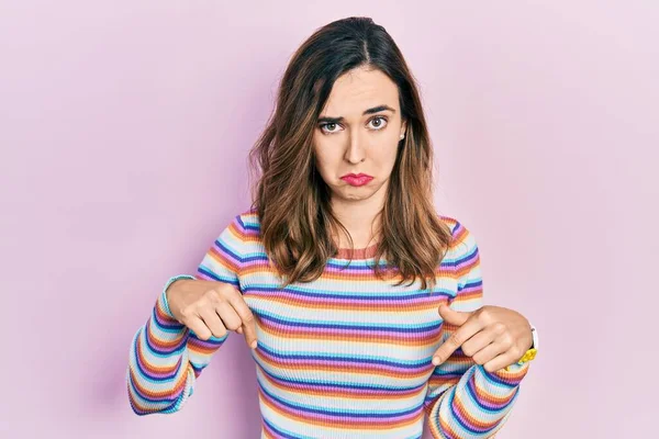 Gündelik kıyafetler giyen genç İspanyol kız üzgün ve üzgün görünüyor, parmaklarıyla yön gösteriyor, mutsuz ve depresif.. 