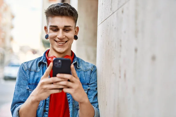 Joven Chico Caucásico Sonriendo Con Teléfono Inteligente Apoyado Pared — Foto de Stock