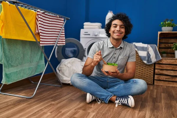Young Hispanic Man Eating Salad Waiting Washing Machine Laundry Room — Stok fotoğraf
