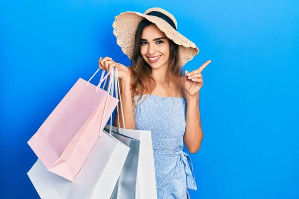 Young Hispanic Girl Holding Shopping Bags Surprised Idea Question Pointing — Stockfoto