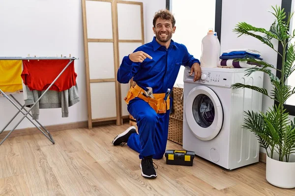 Çamaşır makinesinde çalışan genç İspanyol adam gülümseyen mutlu ve gururlu birini işaret ediyor. 