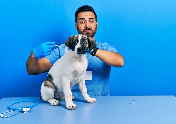 英俊而惊慌的兽医 留着胡子 给小狗注射疫苗 怀疑和紧张 因为问题皱着眉头 消极的人 — 图库照片