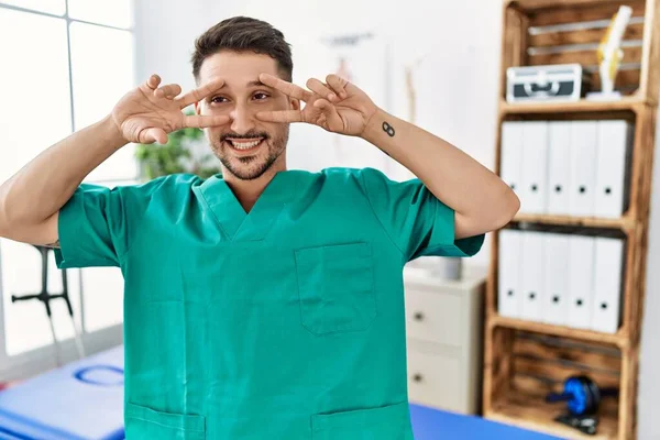 Young Physiotherapist Man Working Pain Recovery Clinic Doing Peace Symbol — Stockfoto