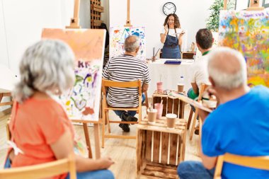 Bir grup orta yaşlı öğrenci resim stüdyosunda resim dersi alıyor..