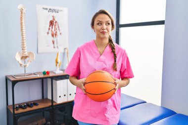 Genç İspanyol kadın fizyoterapi kliniğinde çalışıyor basketbol topu tutuyor gülümsüyor ve başka tarafa bakıyor.. 