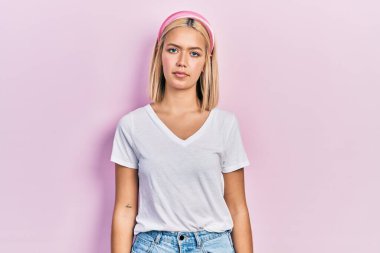 Beautiful blonde woman wearing casual white t shirt relaxed with serious expression on face. simple and natural looking at the camera. 