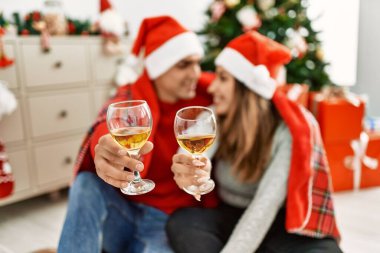 Battaniyeli Noel şapkası takan genç bir çift. Yerde oturup evde şampanyayla kadeh kaldırıyorum..