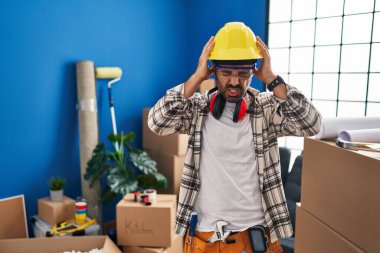 Sakallı, evde çalışan, baş ağrısı çeken, çaresiz ve stresli bir İspanyol genç adam. Ağrı ve migren yüzünden. Eller başının üstünde.. 