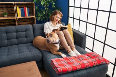 Kafkasyalı genç bir kadın evdeki kanepede köpeğiyle oturuyor.