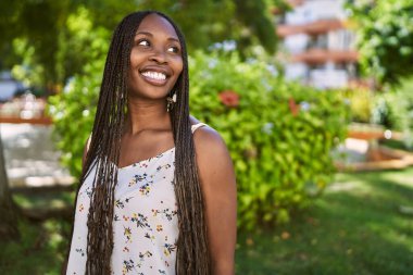 Genç Afrikalı Amerikalı kadın gülümseyerek şehirde mutlu mesut duruyor..