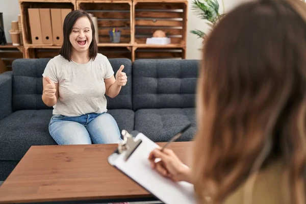 Hispanic girl with down syndrome doing therapy success sign doing positive gesture with hand, thumbs up smiling and happy. cheerful expression and winner gesture.
