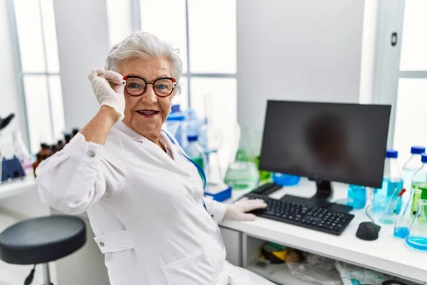 研究室で働くコンピュータを使って科学者の制服を着たシニア白髪の女性 — ストック写真