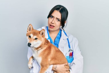 Güzel İspanyol veteriner kadın köpeği tutuyor ve kafası karışık. şüphe kavramı. 
